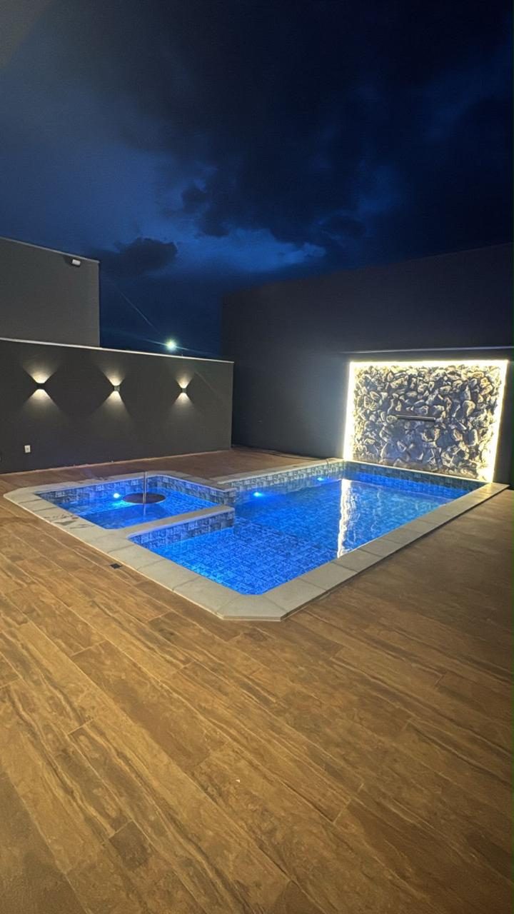 Piscina à noite com iluminação em LED e cascata em parede de pedra