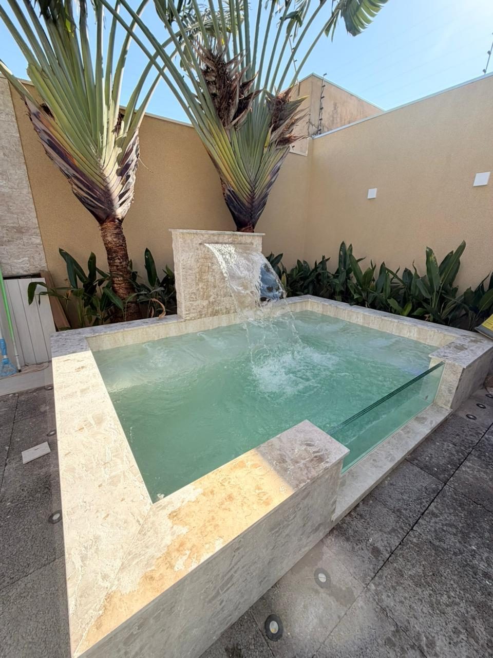 Spa elevado em pedra com cascata e visor de vidro
